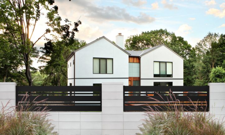 betonowe ogrodzenie firmy JONIEC® z czarnymi poziomymi panelami i eleganckim domem w tle, otoczone zielenią